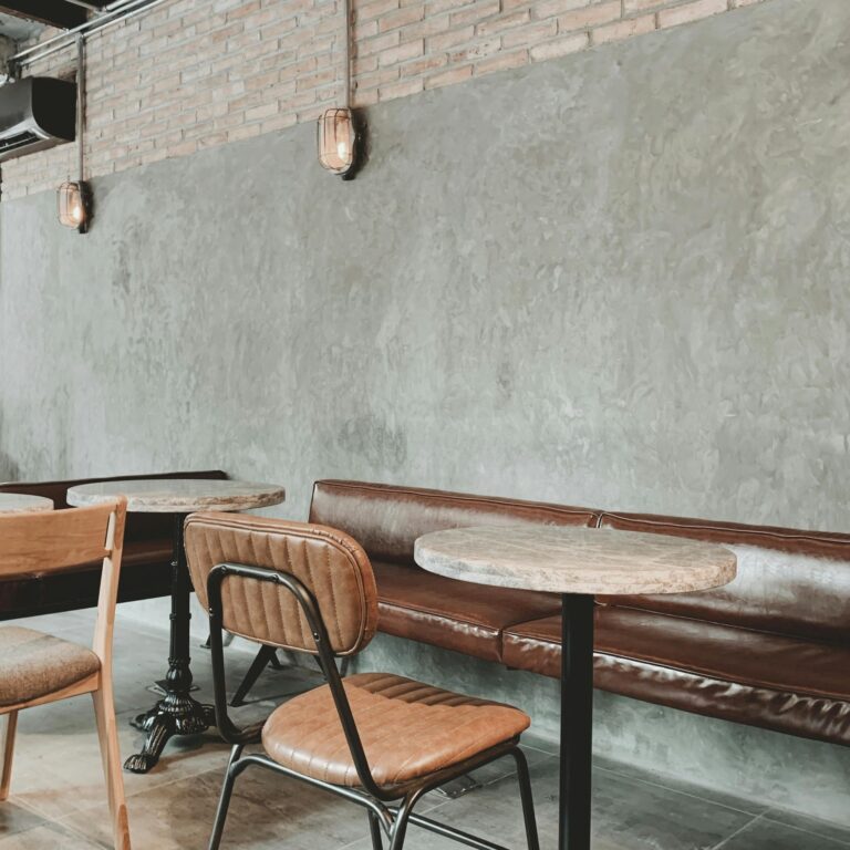 Chic cafe interior with industrial style tables and chairs against a concrete wall.